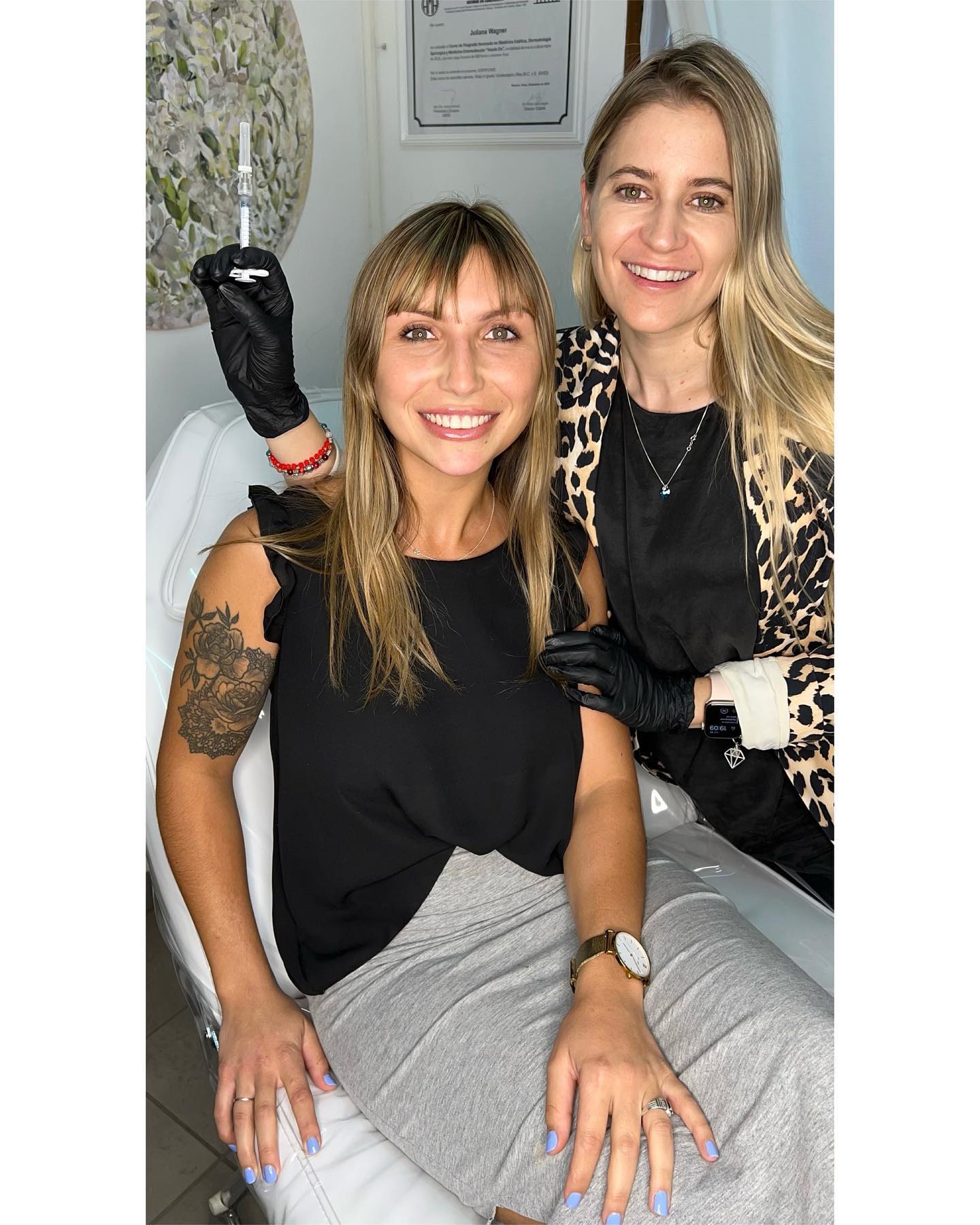 La Dra. Juliana Wagner, con guantes y saco animal print, sonríe junto a una paciente sentada en la camilla del consultorio